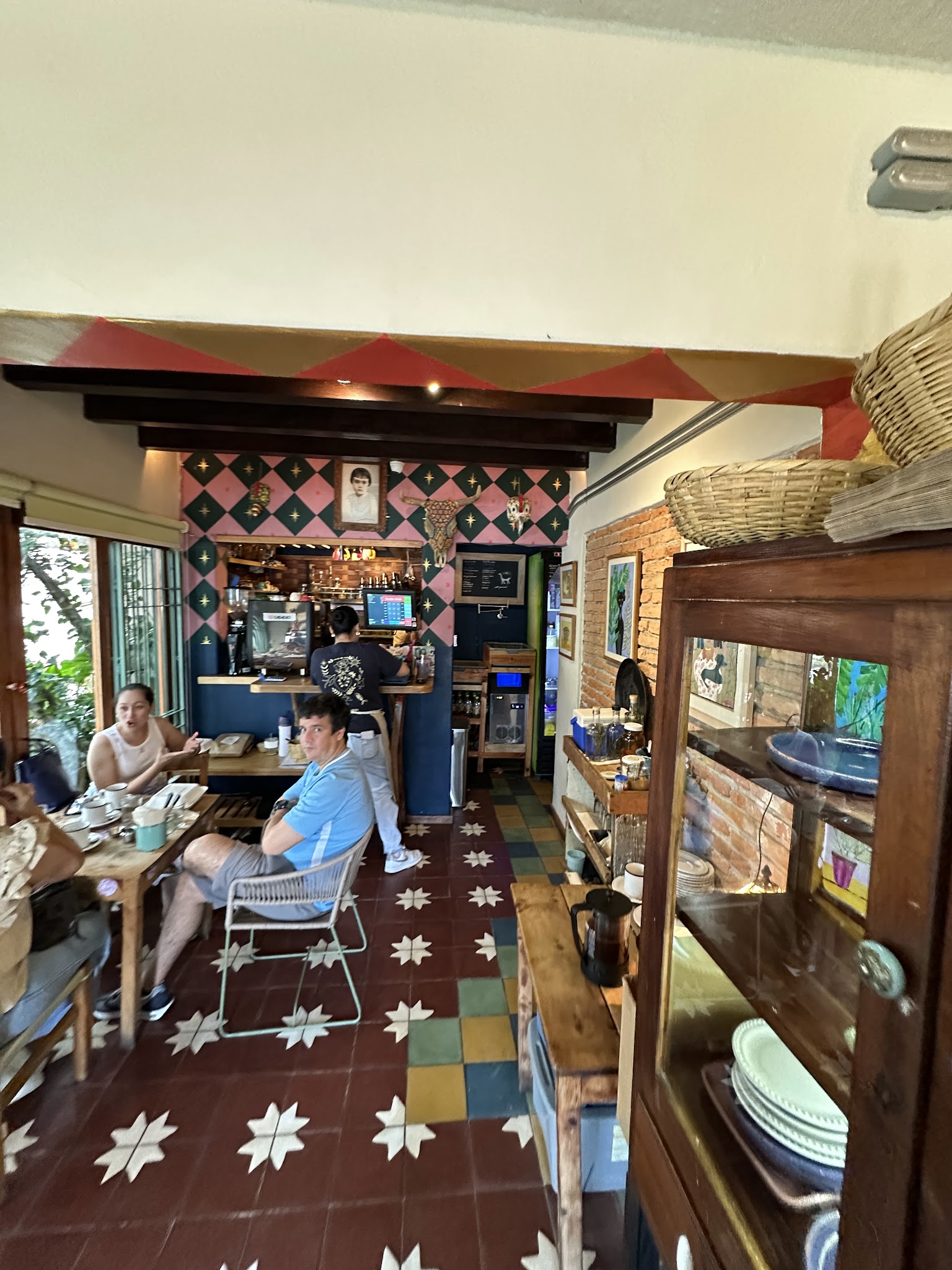 Café La Buena Vida's colorful dining room, with wooden tables and patterned floor tiles.